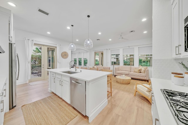 kitchen with white cabinets, sink, decorative backsplash, decorative light fixtures, and stainless steel appliances