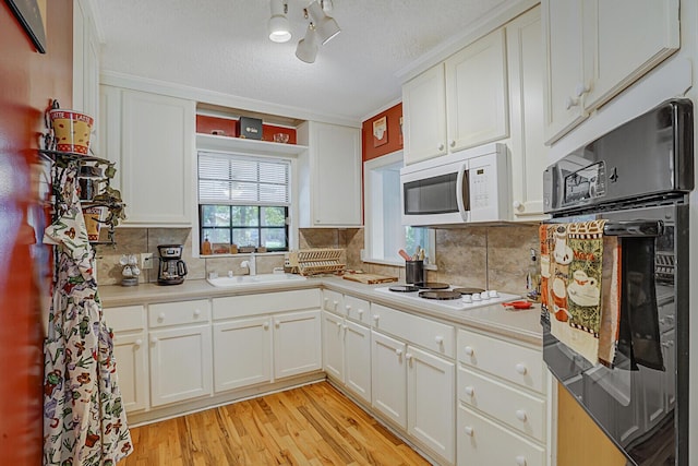 kitchen featuring a textured ceiling, white appliances, sink, light hardwood / wood-style flooring, and white cabinetry