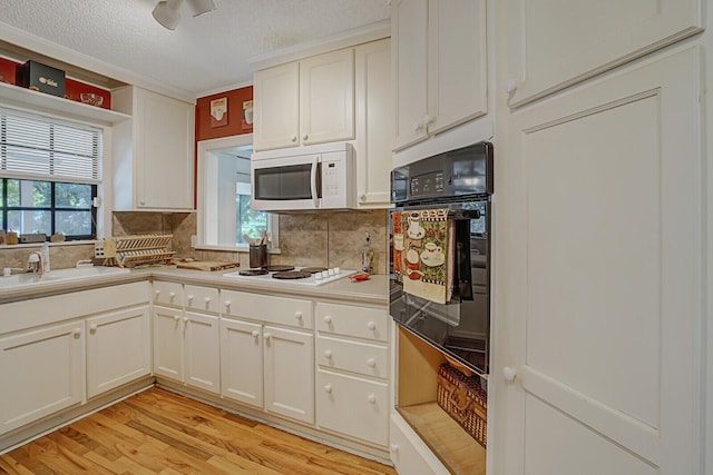 kitchen with a healthy amount of sunlight, light wood-type flooring, white appliances, and sink