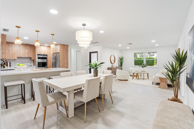 dining area with sink and light wood-type flooring