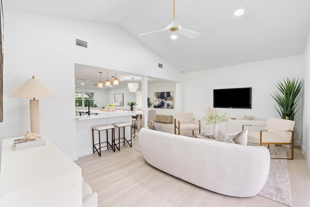 living room with ceiling fan, light hardwood / wood-style floors, and high vaulted ceiling