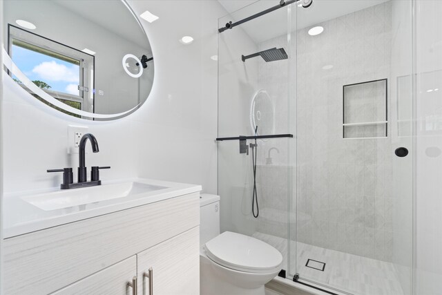 bathroom with vanity, a shower with shower door, and toilet