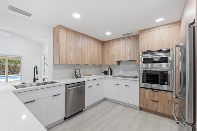 kitchen featuring appliances with stainless steel finishes, light wood-type flooring, light brown cabinetry, sink, and white cabinets