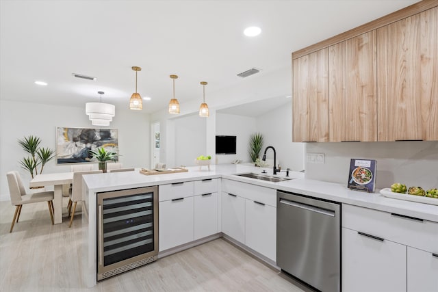 kitchen with kitchen peninsula, stainless steel dishwasher, sink, pendant lighting, and wine cooler