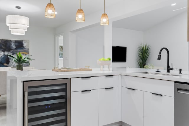 kitchen with pendant lighting, sink, stainless steel dishwasher, white cabinetry, and beverage cooler