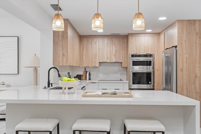 kitchen with decorative light fixtures, light brown cabinets, sink, and appliances with stainless steel finishes