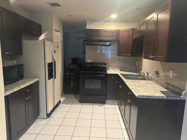 kitchen featuring dark brown cabinetry, ventilation hood, sink, black appliances, and light tile patterned floors