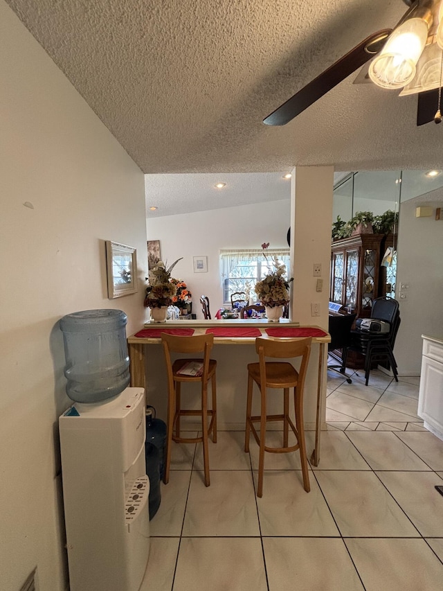 tiled dining room with a textured ceiling and ceiling fan