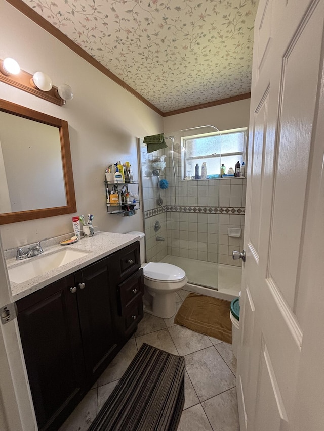 bathroom with vanity, tile patterned floors, toilet, ornamental molding, and tiled shower