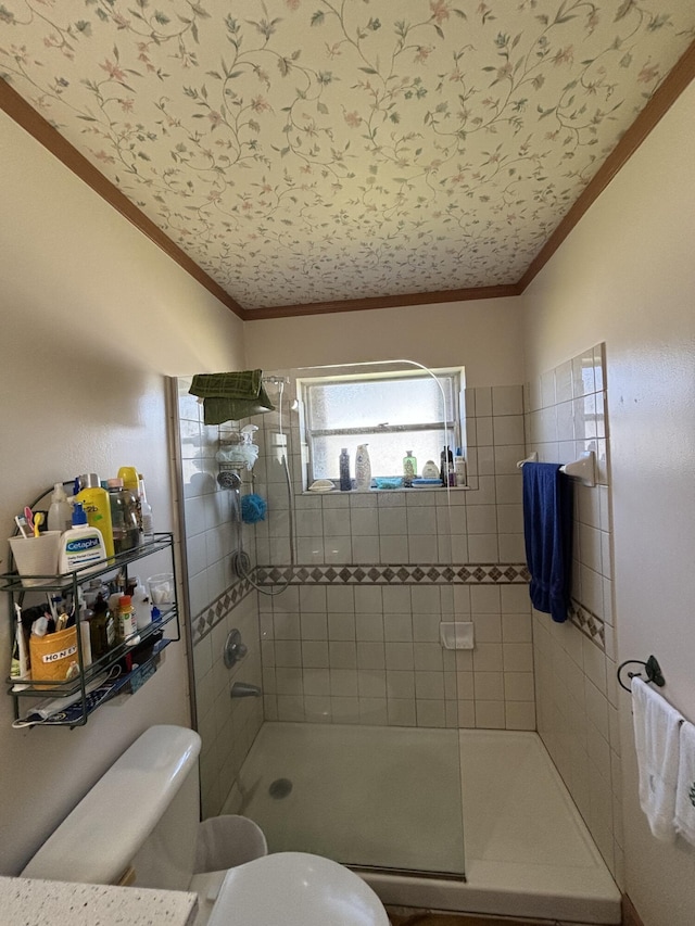 bathroom featuring a tile shower, crown molding, and toilet