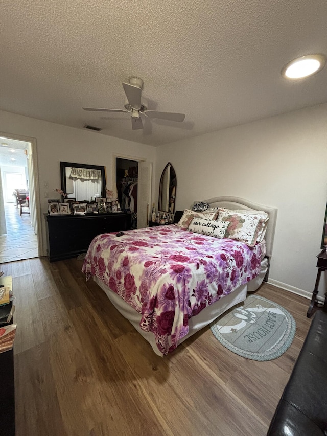 bedroom with dark hardwood / wood-style flooring, a textured ceiling, a closet, and ceiling fan