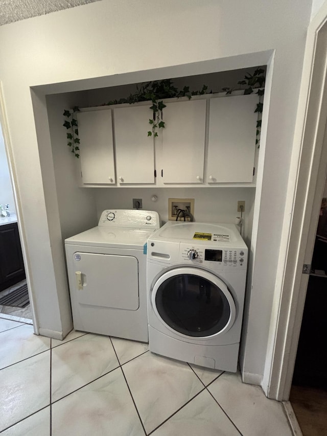 laundry room with cabinets, light tile patterned floors, and separate washer and dryer