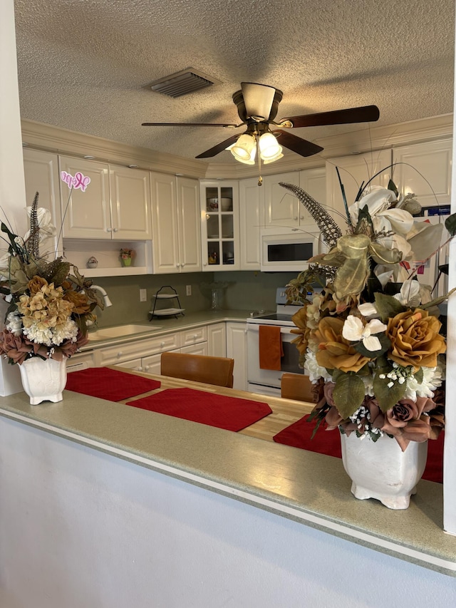 kitchen featuring white cabinetry, sink, ceiling fan, a textured ceiling, and white appliances