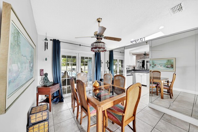 dining space with lofted ceiling, light tile patterned floors, a textured ceiling, and ceiling fan