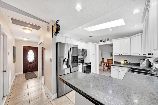 kitchen with light tile patterned flooring, sink, white cabinetry, a textured ceiling, and stainless steel appliances