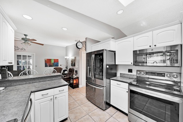 kitchen with white cabinetry, light tile patterned floors, vaulted ceiling, and appliances with stainless steel finishes