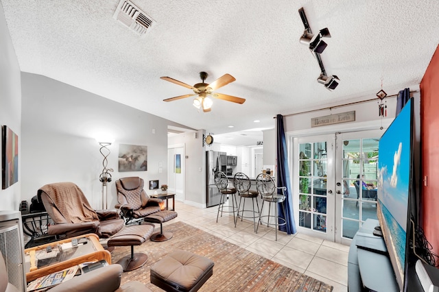 living room with rail lighting, ceiling fan, a textured ceiling, light tile patterned flooring, and french doors