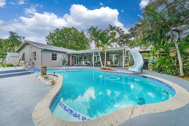 view of pool featuring french doors, a water slide, and a patio area