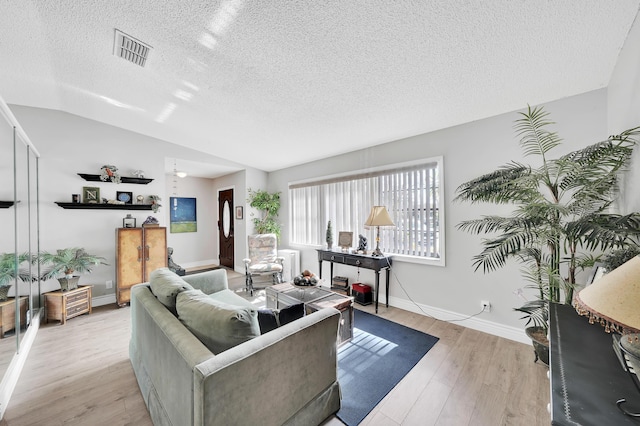 living room featuring lofted ceiling, a textured ceiling, and light wood-type flooring