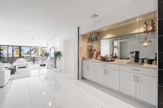 interior space featuring white cabinets, light tile patterned floors, a wall of windows, and hanging light fixtures