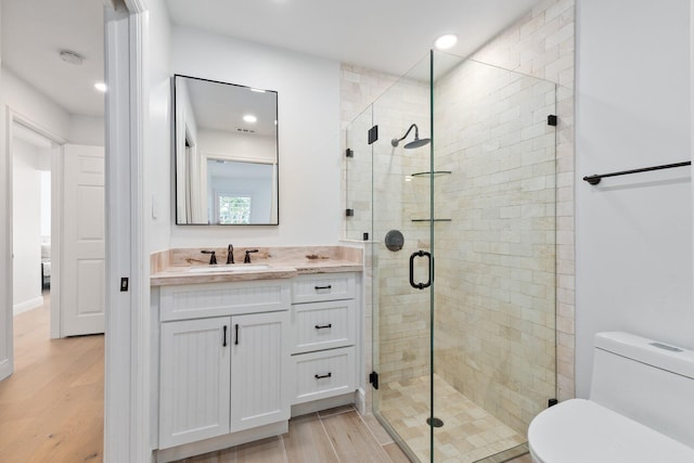 bathroom featuring vanity, wood-type flooring, a shower with door, and toilet