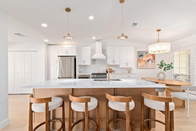 kitchen featuring decorative light fixtures, stainless steel refrigerator, custom range hood, a large island, and white cabinets