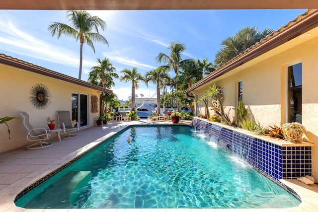 view of swimming pool with pool water feature and a patio area