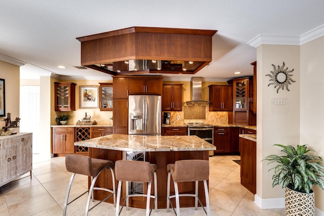 kitchen with a kitchen island, wall chimney range hood, crown molding, and appliances with stainless steel finishes