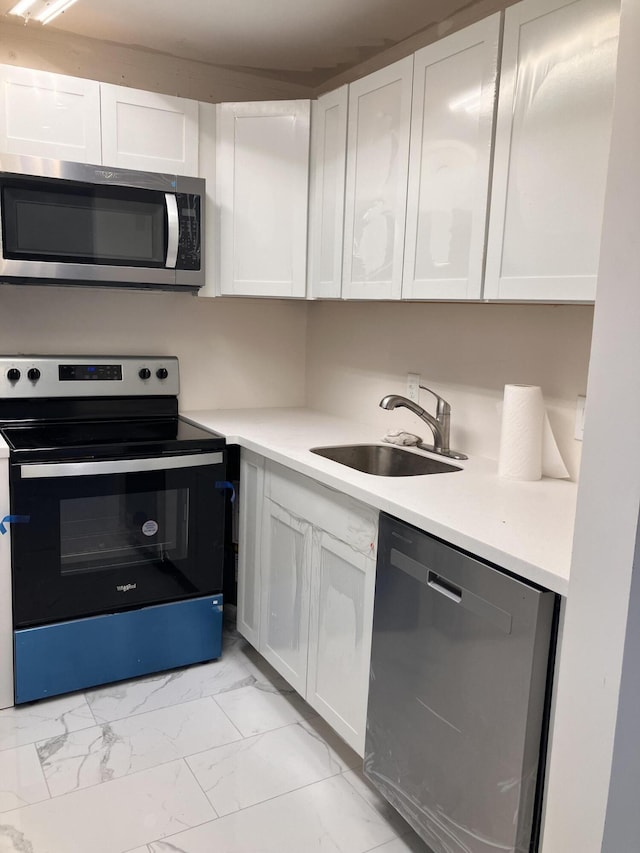 kitchen featuring appliances with stainless steel finishes, white cabinetry, and sink