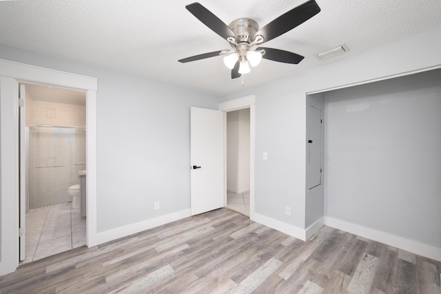 unfurnished bedroom with ceiling fan, light wood-type flooring, a textured ceiling, and connected bathroom