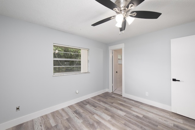 spare room featuring ceiling fan, light wood-type flooring, and a textured ceiling