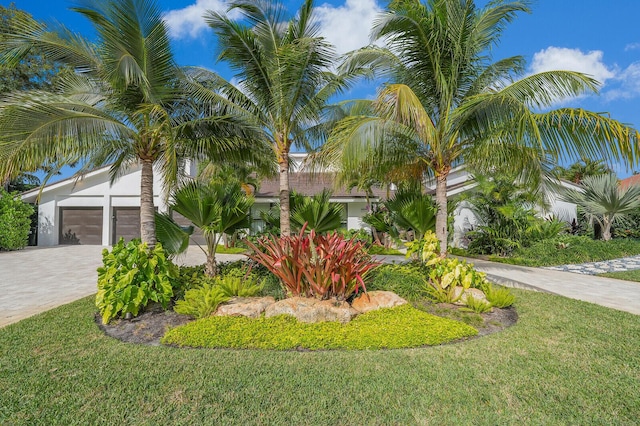 obstructed view of property featuring a garage, a front yard, and decorative driveway