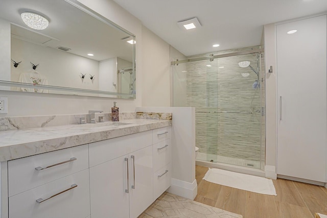 bathroom featuring toilet, vanity, a shower with door, and hardwood / wood-style floors