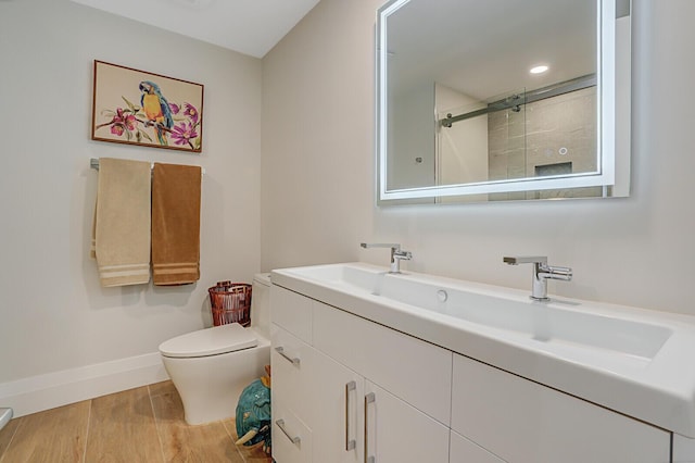 full bathroom with a stall shower, baseboards, toilet, wood finished floors, and vanity