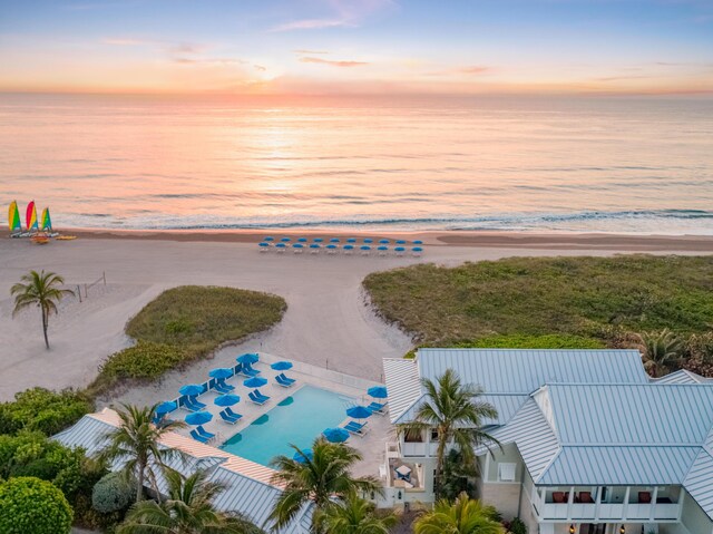 aerial view at dusk featuring a beach view and a water view