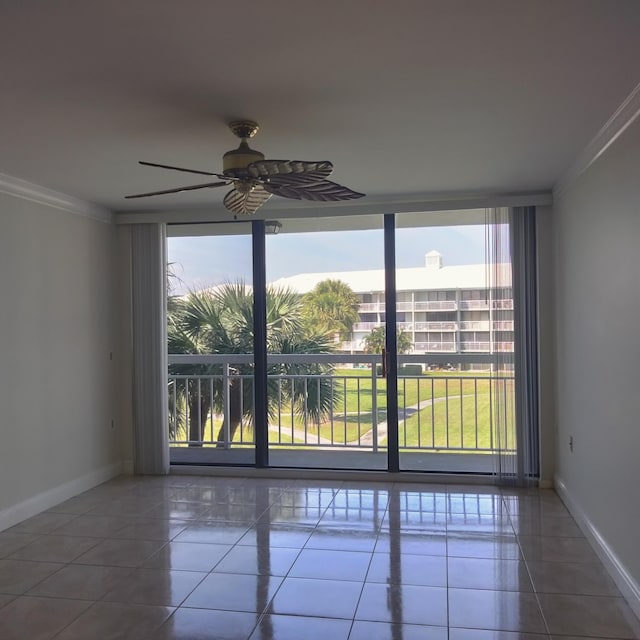 spare room featuring tile patterned floors, expansive windows, baseboards, and ornamental molding