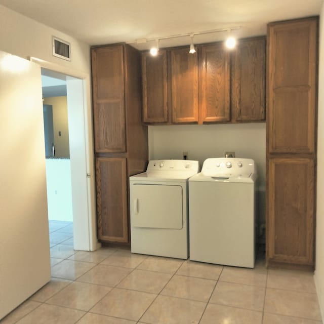 laundry room featuring visible vents, cabinet space, light tile patterned flooring, and washing machine and clothes dryer