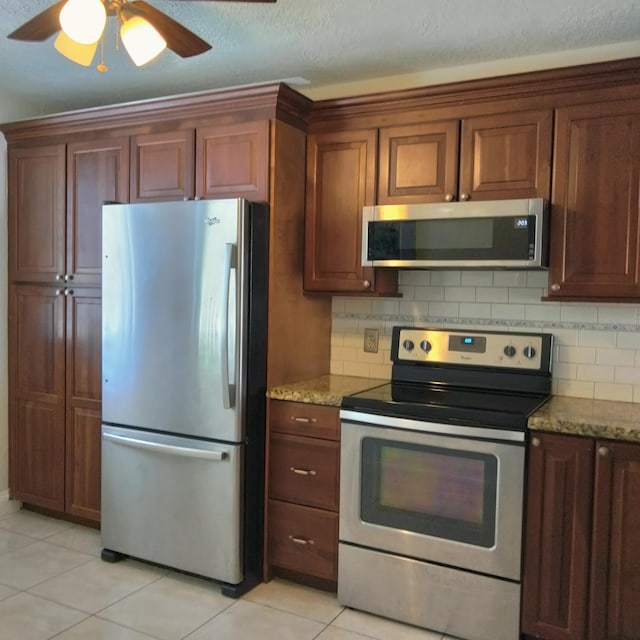 kitchen with light tile patterned flooring, decorative backsplash, stone counters, and appliances with stainless steel finishes