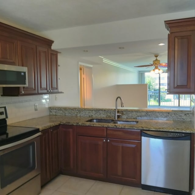 kitchen featuring appliances with stainless steel finishes, light stone countertops, ceiling fan, and a sink