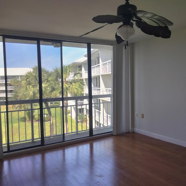 unfurnished room with floor to ceiling windows, wood finished floors, baseboards, and ceiling fan