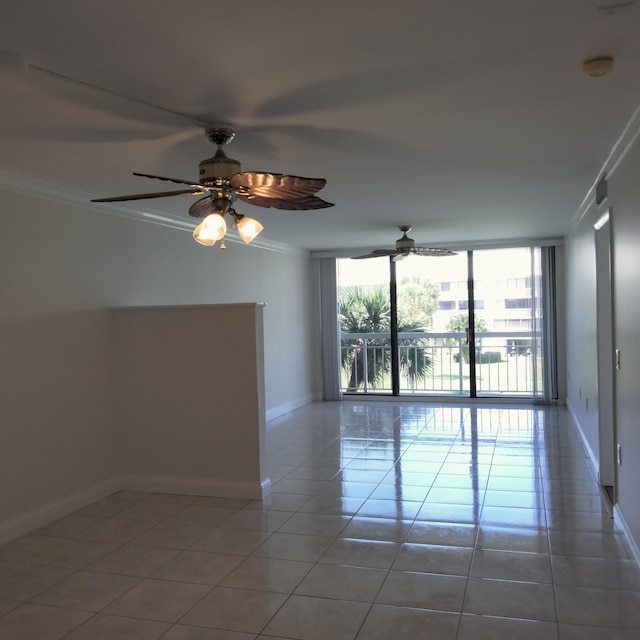 tiled spare room with ceiling fan, floor to ceiling windows, baseboards, and ornamental molding