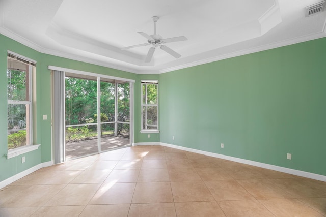 tiled empty room with ceiling fan, a raised ceiling, and ornamental molding