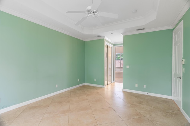 tiled spare room with a raised ceiling, ceiling fan, and ornamental molding