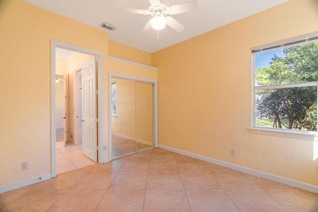 unfurnished bedroom with multiple windows, a closet, ceiling fan, and light tile patterned flooring