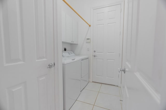 laundry area featuring washer and clothes dryer, cabinets, and light tile patterned floors