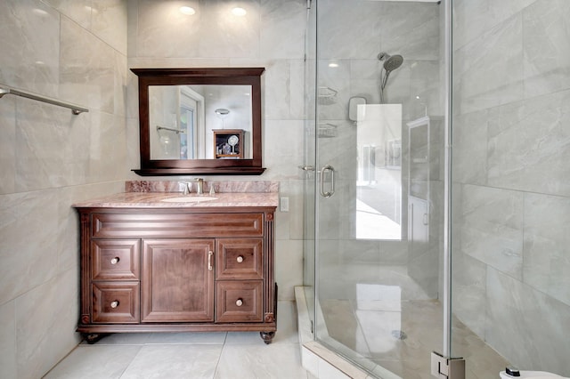 bathroom with tile walls, vanity, and an enclosed shower