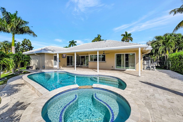 view of swimming pool with ceiling fan, a patio area, and an in ground hot tub