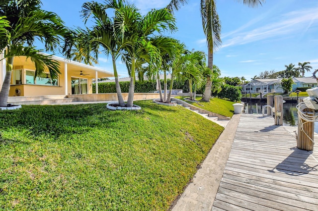 view of yard with ceiling fan, a water view, and a boat dock