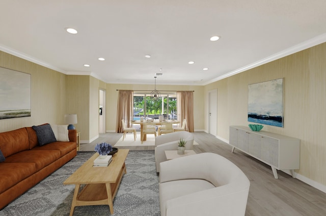 living room featuring an inviting chandelier, light hardwood / wood-style flooring, and crown molding