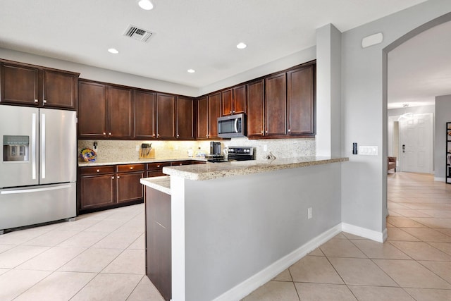 kitchen with light tile patterned flooring, electric range oven, tasteful backsplash, light stone countertops, and fridge with ice dispenser